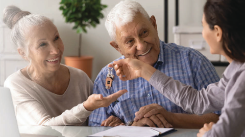 REALTOR giving keys to happy older couple